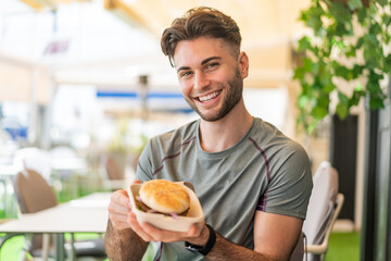 Young handsome man holding a burger