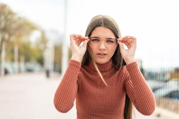 Teenager girl at outdoors With glasses and frustrated expression