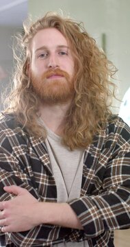 Vertical video of portait of caucasian male hairdresser smiling at hair salon, in slow motion