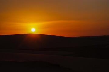 Naklejka na ściany i meble Sunset and sunrise in the desert with beautiful sand dunes behind it 