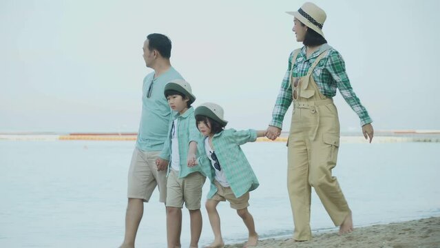 happy asian family walking together on beach in holiday in summer vacation . Father mother and children of Four  travel outdoors . family same color clothes