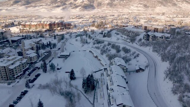 Aerial reveal of steamboat springs city, condos, mountain, and road in winter