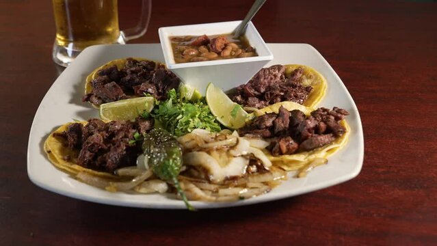 Four traditional street tacos paired with borracho pinto beans and beer, slider 4K