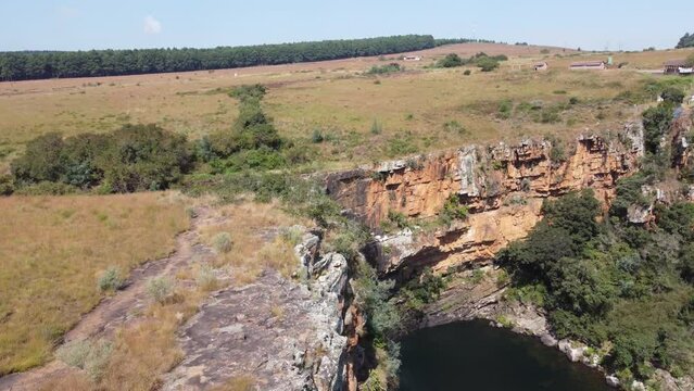 Revealing Berlin Falls waterfall in South Africa. Drone flying towards rugged red cliff