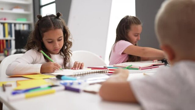 Adorable girls students sitting on table drawing on notebook at classroom