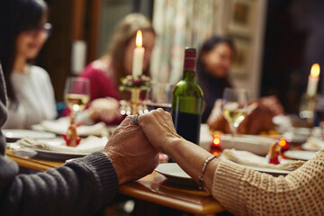 Family, people holding hands in prayer and at dinner table with champagne. Praying for food, support or love and adults gather for celebration or thanksgiving in dining room at their home. - obrazy, fototapety, plakaty