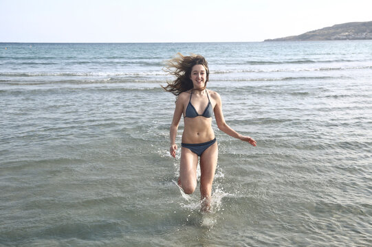 young woman runs into the sea water