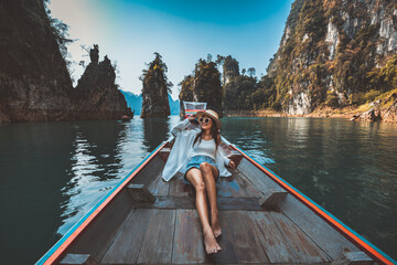 Traveler asian woman relax and travel on Thai longtail boat in Ratchaprapha Dam at Khao Sok National Park Surat Thani Thailand - 602020731