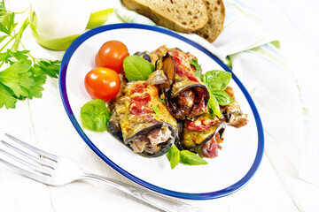 Rolls of eggplant with meat in plate on wooden table