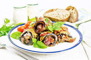 Rolls of eggplant with meat in plate on board