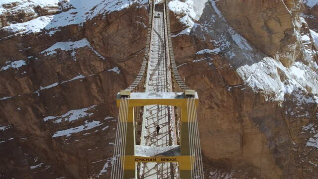 Aerial view of the Chicham bridge and snowy mountains in background during winter season. World's highest suspension bridge at Chicham, Spiti Valley, India. Drone shot. 4K