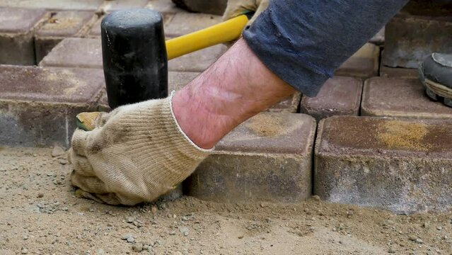Paving slabs.The hands of a road worker are shifting paving slabs, repairing the road surface.