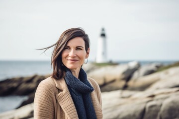 Portrait of a beautiful woman standing in front of a lighthouse on the beach