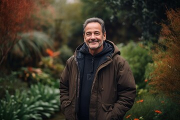 Handsome middle-aged man smiling and looking at camera while standing in garden