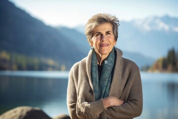 Fototapeta na wymiar Portrait of a happy senior woman with arms crossed on lake background