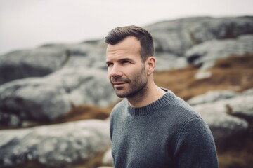 Fototapeta na wymiar Portrait of a handsome man in a gray sweater on the rocks