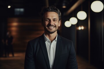 Fototapeta premium Portrait of handsome young businessman looking at camera and smiling while standing indoors