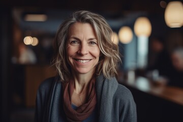 Portrait of happy mature woman smiling at camera while standing in cafe