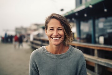 Portrait of a smiling young woman standing on the pier at the seaside