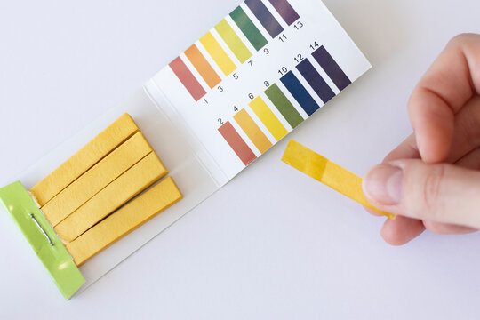 Water pH measurement test. Yellow strip in a woman's hand