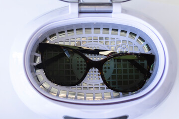 Washing sunglasses in an ultrasonic wash on a white background