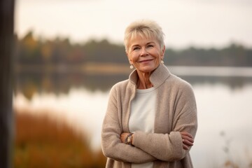 Fototapeta na wymiar Portrait of a happy senior woman standing by the lake in autumn