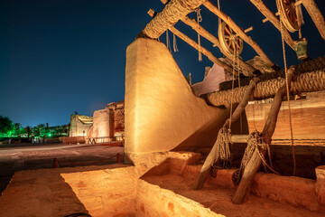 Diriyah old town well with highlighted wall in the background at night, Riyadh, Saudi Arabia