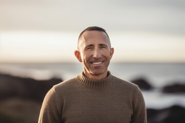 Fototapeta na wymiar Medium shot portrait photography of a pleased man in his 40s wearing a cozy sweater against a beach sunset background. Generative AI