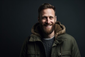 Obraz premium Portrait of a smiling bearded man in a warm jacket on a dark background