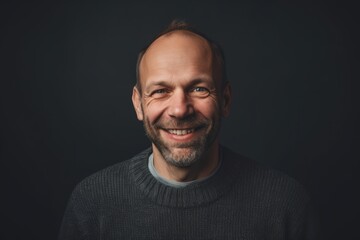 Fototapeta premium Portrait of a smiling middle-aged man on black background.