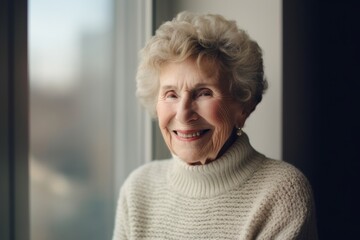 Fototapeta na wymiar Portrait of a smiling senior woman standing by the window at home