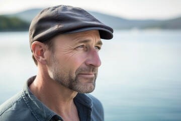 Portrait of mature man with cap looking away at lake in the countryside