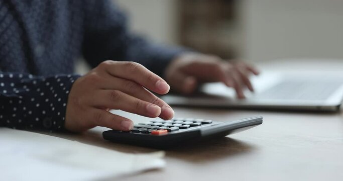 Close up of female hands accountant auditor do work at desk, use calculator calculates incomes and expenses, pay for loan, enter data result in laptop app, planning budget, manage personal payments