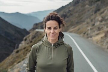 Portrait of a smiling middle-aged woman standing on a mountain road