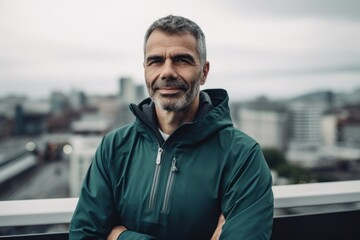 Portrait of a handsome middle-aged man in sportswear standing on the roof of a skyscraper.