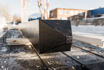 Close-up of the tip of a black reinforced concrete pile, the product is covered with bituminous waterproofing used in the construction of pile foundations.