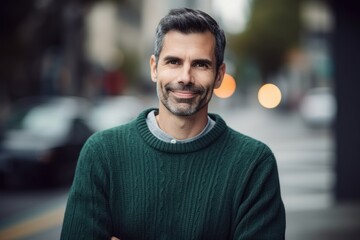 Fototapeta premium Portrait of handsome man in green sweater standing in the city street