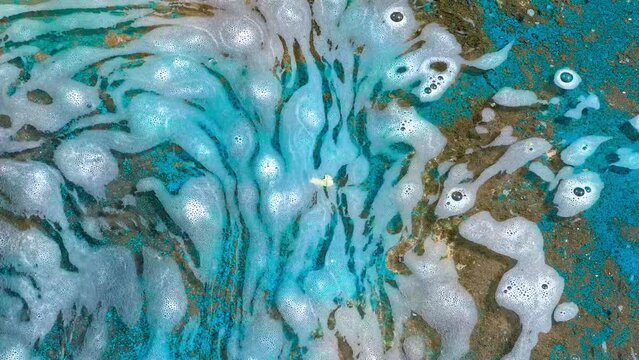Chemical contaminants in water on which foam floats.