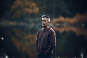 Portrait of a handsome man in a sweater standing by the lake
