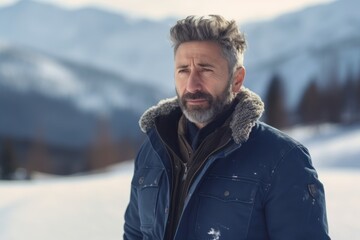 Fototapeta na wymiar Portrait of a handsome middle-aged man with gray hair in a blue jacket in the mountains