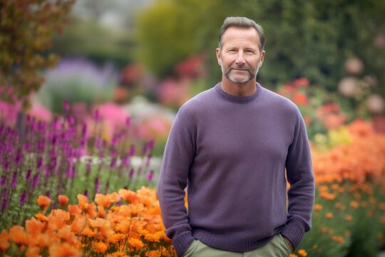 Environmental portrait photography of a pleased man in his 40s wearing a cozy sweater against a colorful flower garden background. Generative AI