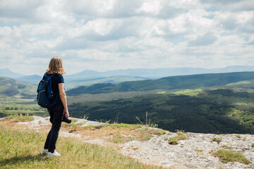 Naklejka na ściany i meble a woman on the mountain looks into the distance admiring nature journey hiking