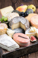 Traditional party platter with soft cheese and fruits served  as close-up on a rustic wooden design board