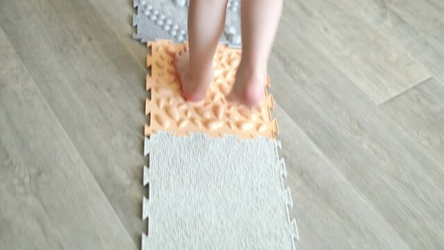 Close-up of children's feet walking on a special massage mat. Massage of the nerve endings of the legs, prevention of flat feet in children. Foot deformity treatment