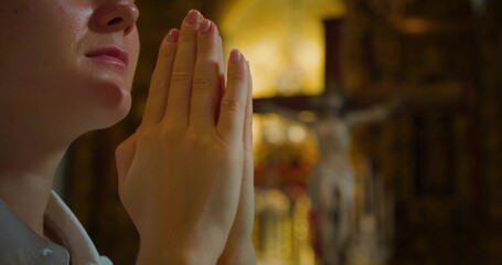 Christian woman folded hands in prayer in church. Close-up adult girl face with closed eyes.