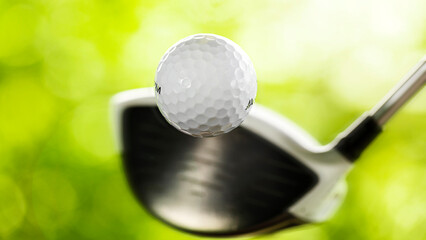 Golf ball hit for drive on golf course with defocused background and selective focus on golf...