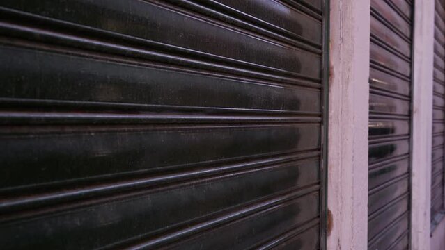 black closed shutters on windows of store in city street