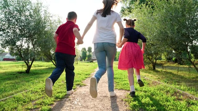 Mom, child, son, daughter play, run in summer April holding hands. Happy running kids boy girl, mom in nature. Weekend with family. In summer, family walks outdoors. Sports seed team. Family holiday