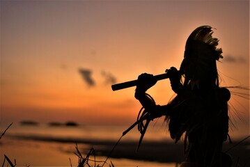 A Native American Indian plays music on a bamboo flute.
