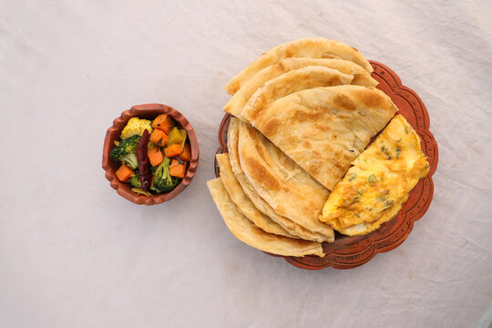 desi breakfast mixed vegetables, egg omelet and paratha served in dish isolated on background top view of bangladesi breakfast